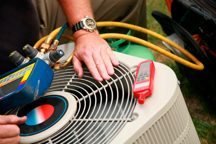 Technician From Bloomington Heating & Air Repairing An Air Conditioner In Bloomington, MN