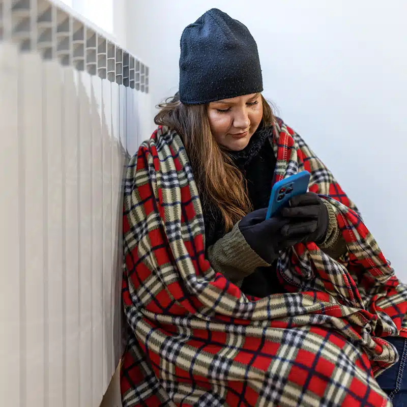 woman wrapped in blanket next to heater