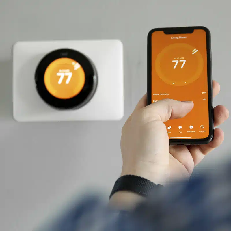 man adjusting thermostat with phone